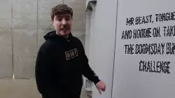 Mr Beast, tongue out and hoodie on, taking on the doomsday bunker challenge meme
